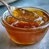 A golden jar of dandelion jelly with delicate floral notes, perfect for spreading on warm toast or scones.