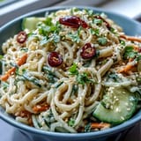 Refreshing cold sesame noodle bowl with julienned cucumber, sesame seeds, and zesty lime, perfect for a light summer meal.