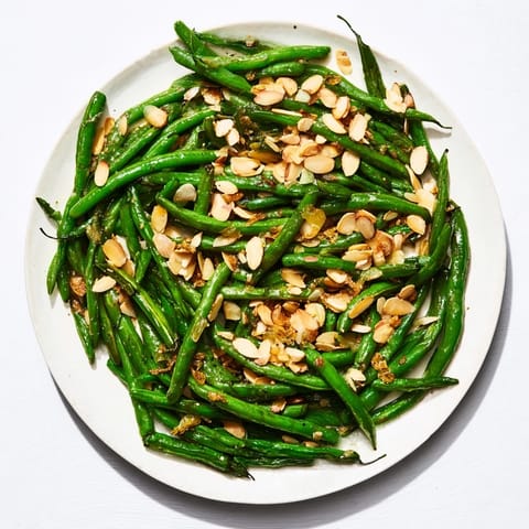 Fresh Sautéed Green Beans with Garlic and Almonds glistening with olive oil and fragrant garlic, ready to serve.