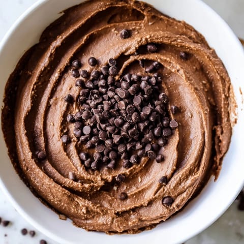 Homemade chocolate hummus, a creamy vegan dessert dip with a dusting of extra chocolate chips.