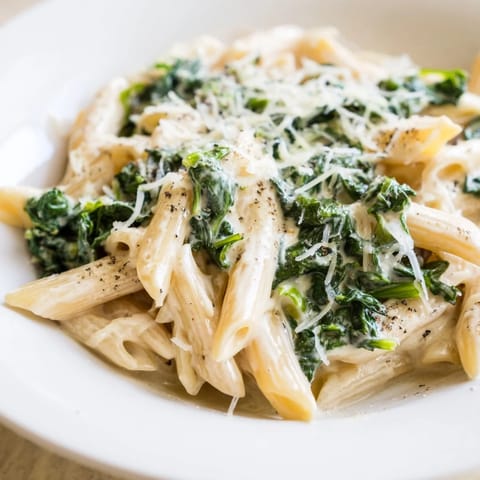 Close-up of creamy spinach pasta, showing perfectly cooked penne in rich, cheesy sauce.