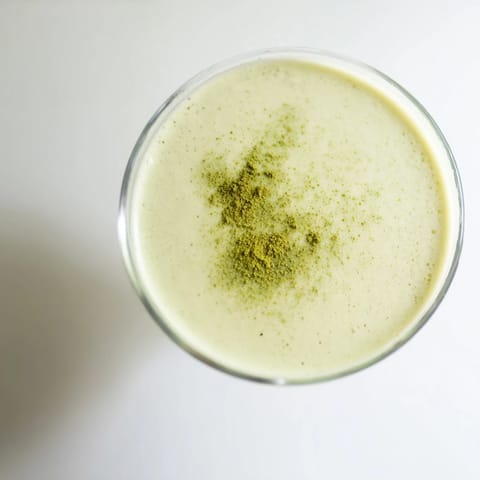 An overhead view of a Matcha Martini Cocktail ingredients: matcha, vodka, and cream, ready for shaking into a frothy drink.