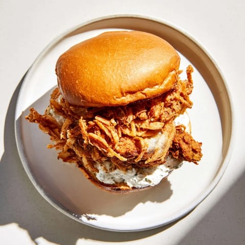 Buttermilk-marinated chicken sandwich topped with crunchy fried onions and a smear of garlic aioli.
