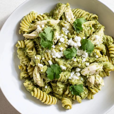 Cilantro lime chicken pasta served warm with fresh cilantro and lime wedges on a rustic wooden table.  
