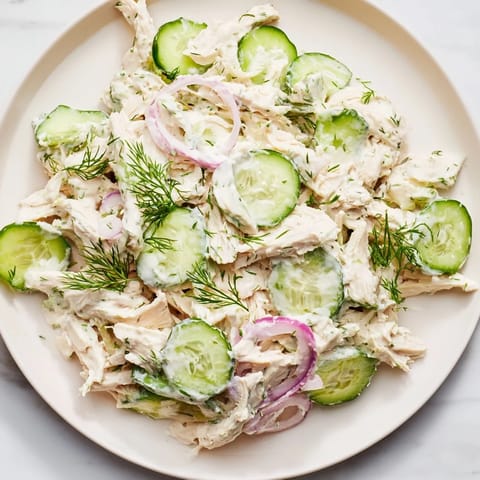 Close-up of Creamy Cucumber Chicken Salad with tender chicken, cool cucumber, and creamy yogurt dressing, served on a rustic wooden table.