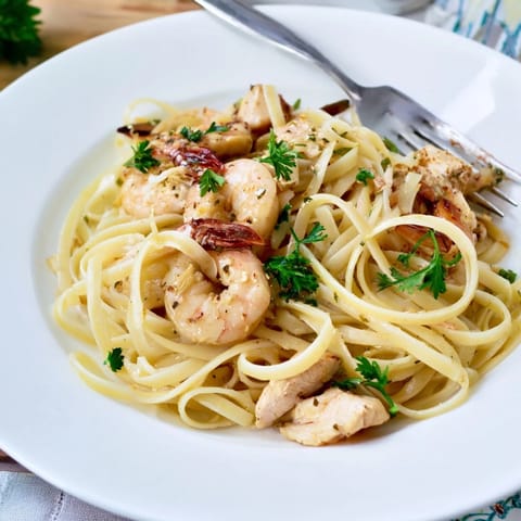 Fork-tender chicken and succulent shrimp tossed in a vibrant lemon-garlic butter sauce over a bed of al dente linguine.  