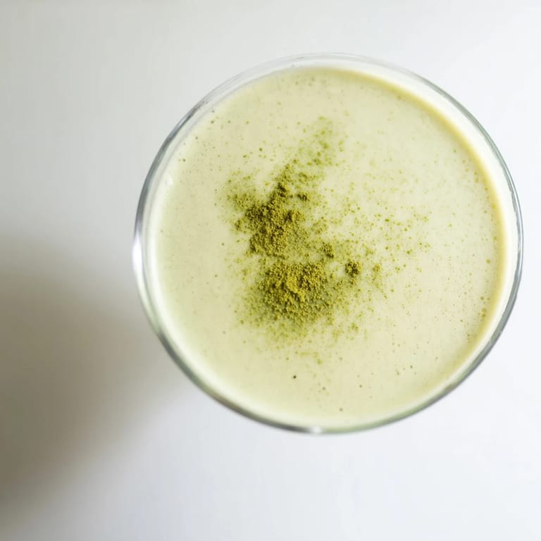 An overhead view of a Matcha Martini Cocktail ingredients: matcha, vodka, and cream, ready for shaking into a frothy drink.