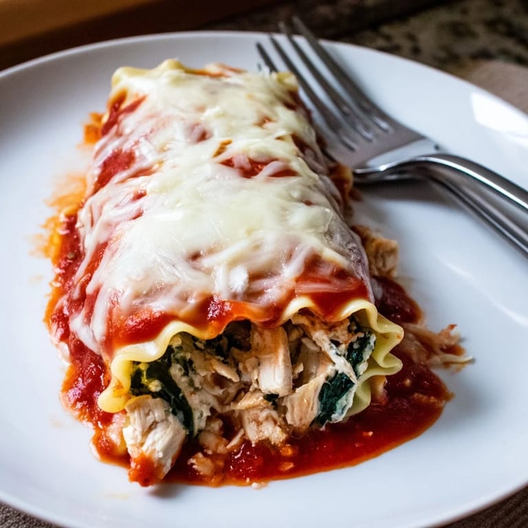 Close-up of a halved Chicken and Spinach Lasagna Roll revealing tender shredded chicken, chopped spinach, and ricotta cheese inside.