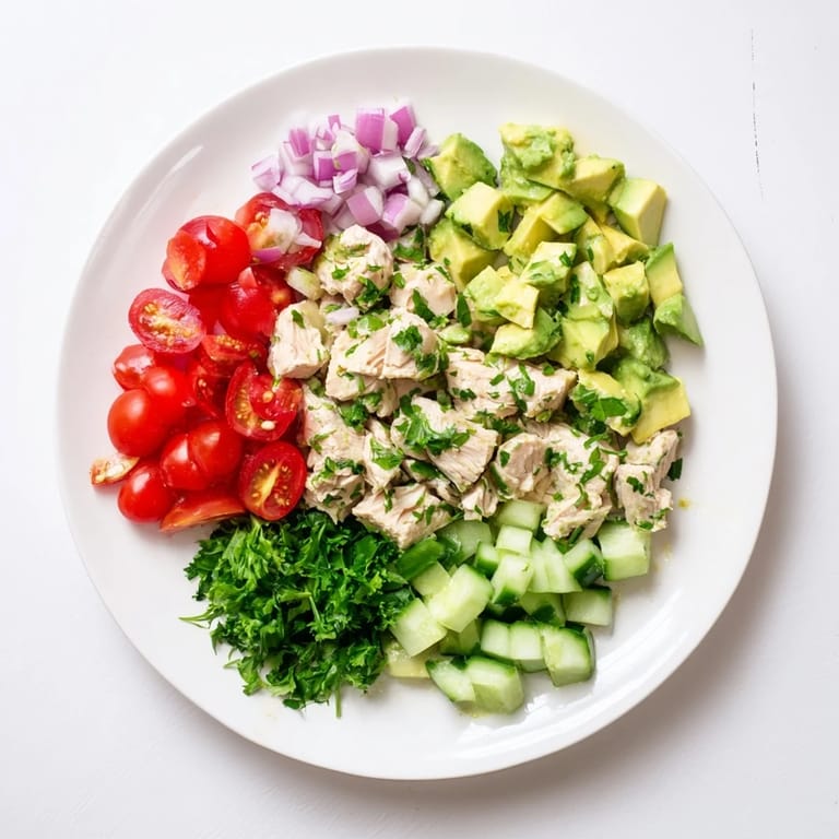 A close-up of the Avocado Chicken Salad, showcasing diced avocado, juicy cherry tomatoes, and fresh cilantro in a light lime dressing.