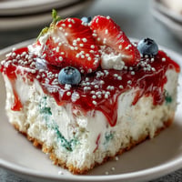 Festive Memorial Day Red White Blue Poke Cake with creamy topping and sprinkles.